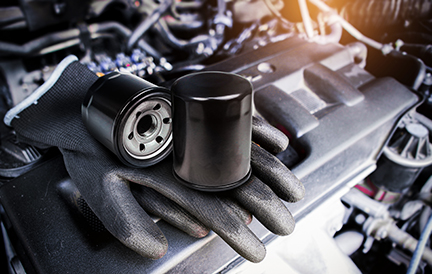 Engine oil filter and auto mechanic gloves on engine cover in a engine compartment for car engine maintenance , Car maintenance service concept. Ancillaries